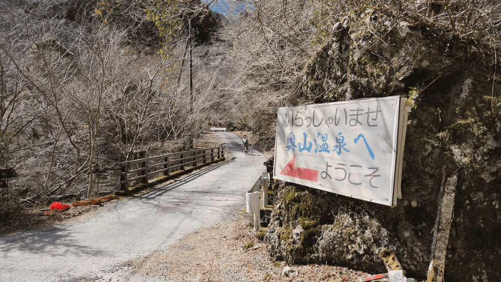 「いらっしゃいませ 奥山温泉へ ようこそ」の看板と林道